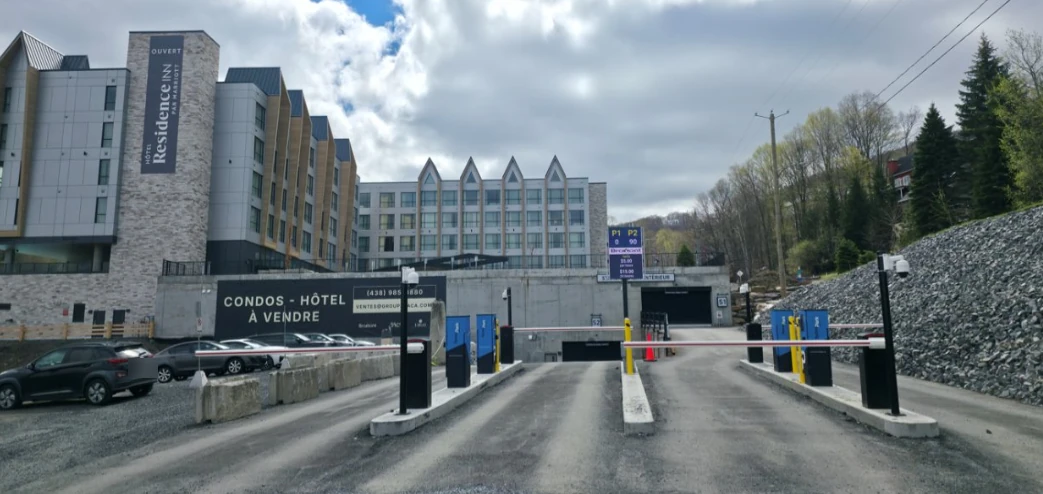 A NoctoPark lane at a hotel in Bromont: LPR camera on its post, payment station, live space sign and the barrier.